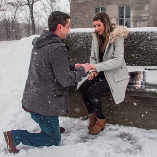 A man proposes to a woman on a bench.