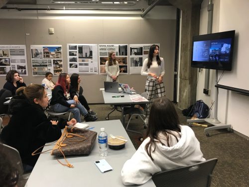 Two students present interior designs to a class