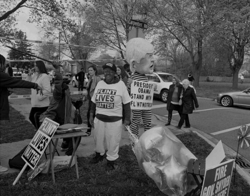 People protest outside with signs.