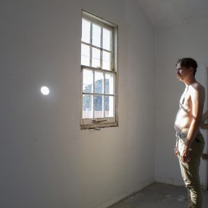 A person stands in front of a window.
